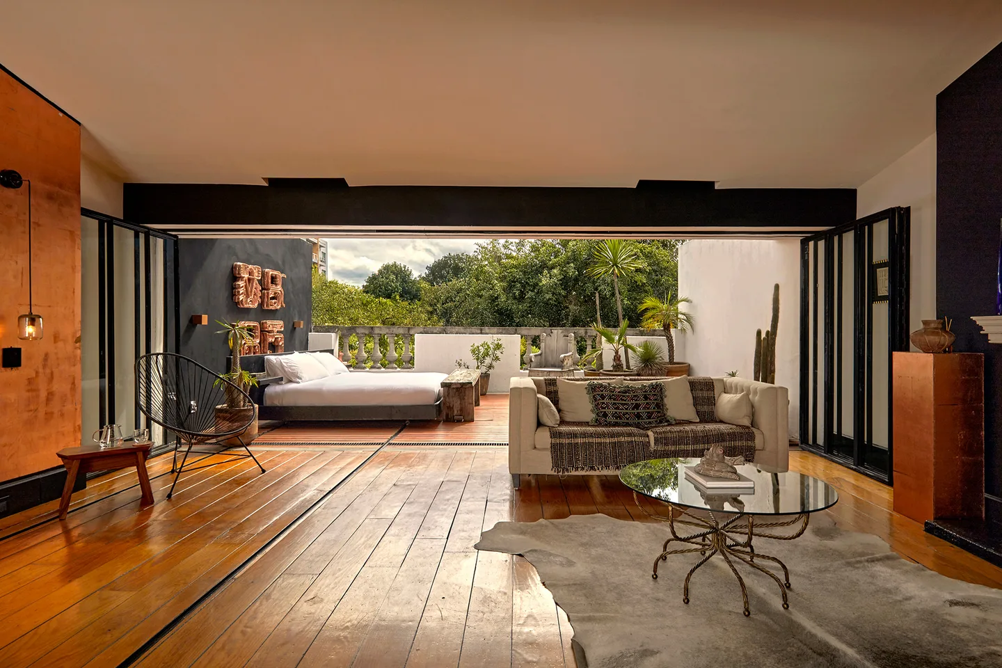 Suite fully open to the terrace, with the lounge in the foreground and the bed outside — Polaris Suite, La Valise Mexico City