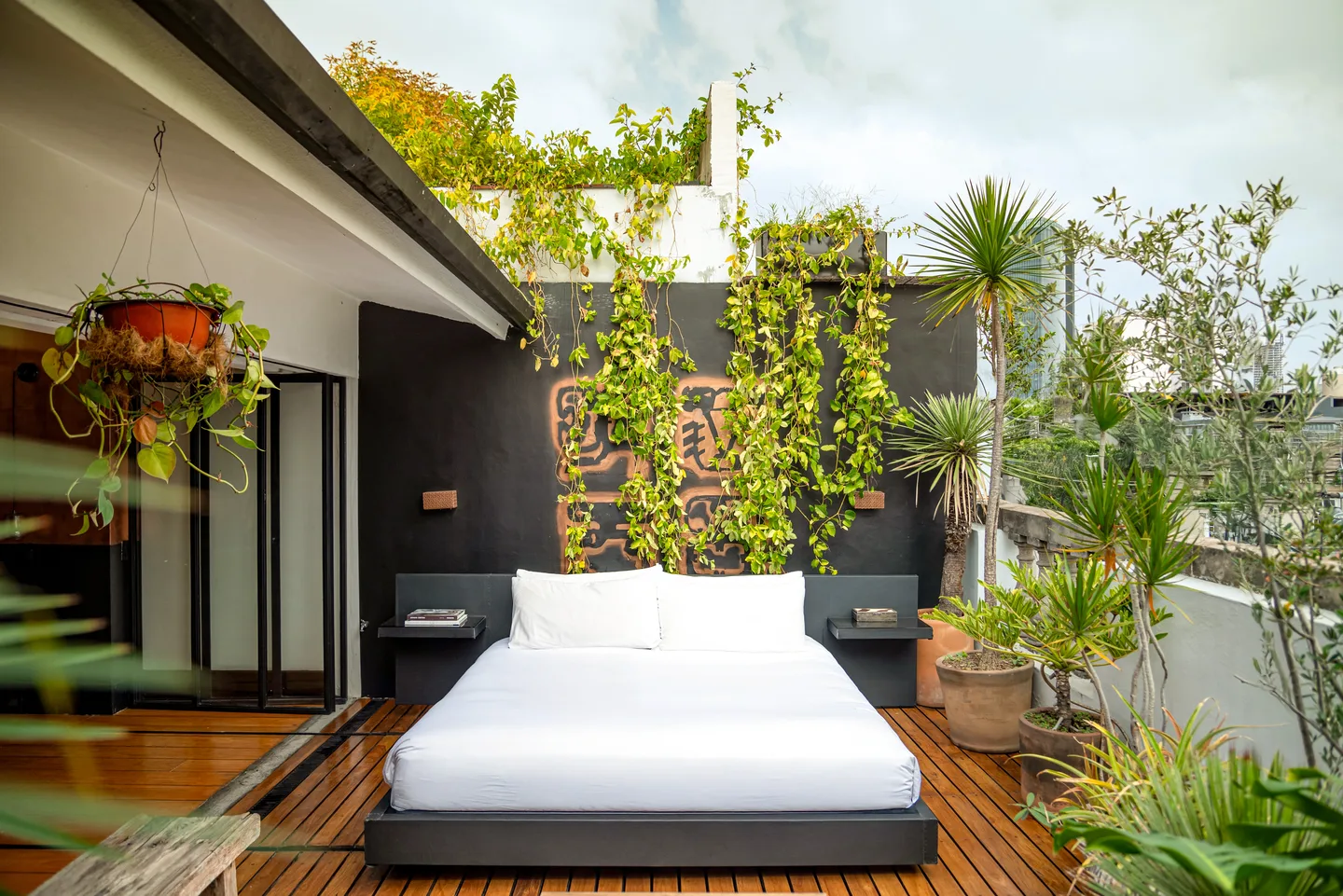 King-size bed rolled out onto the private terrace beneath a green wall — Polaris Suite, La Valise Mexico City