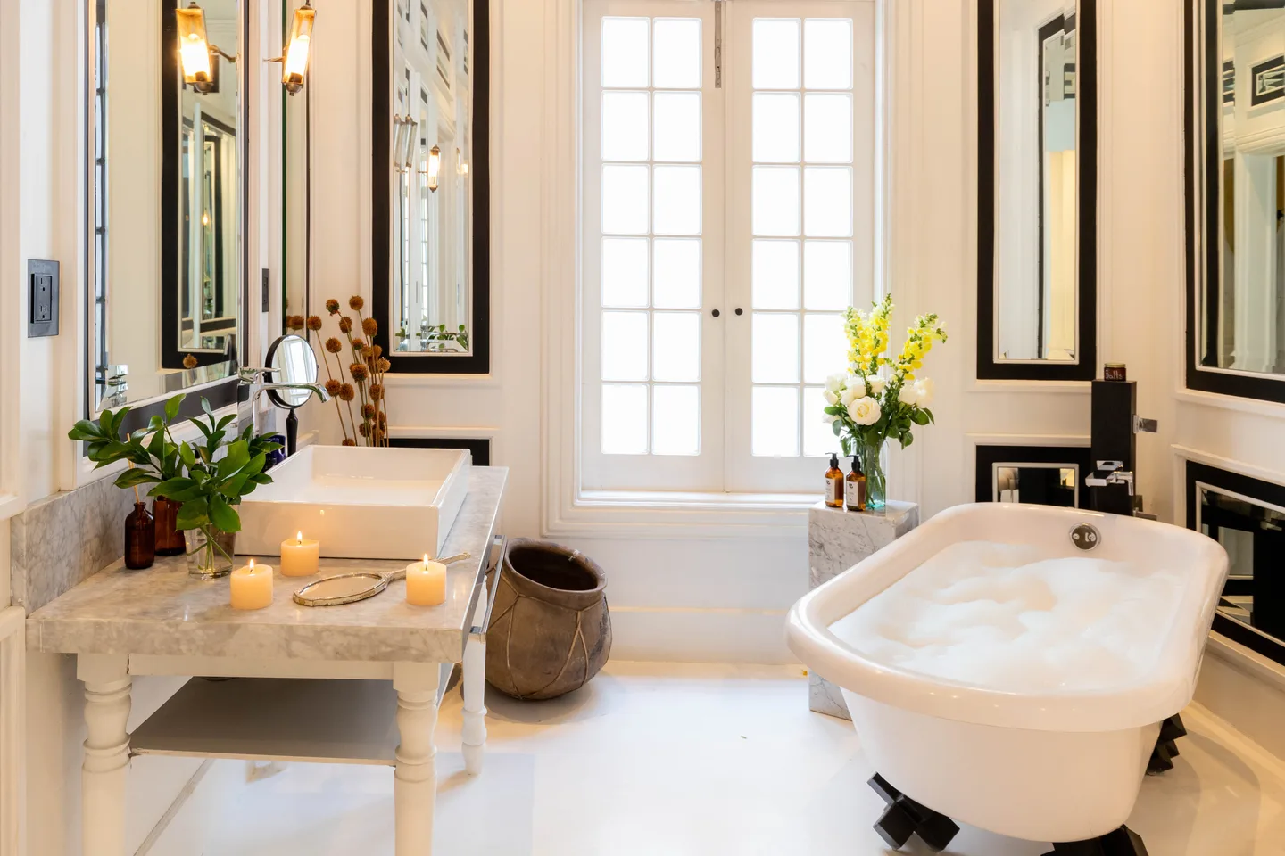 Clawfoot bathtub and vanity lit by candles beside French windows — Moon Suite, La Valise Mexico City