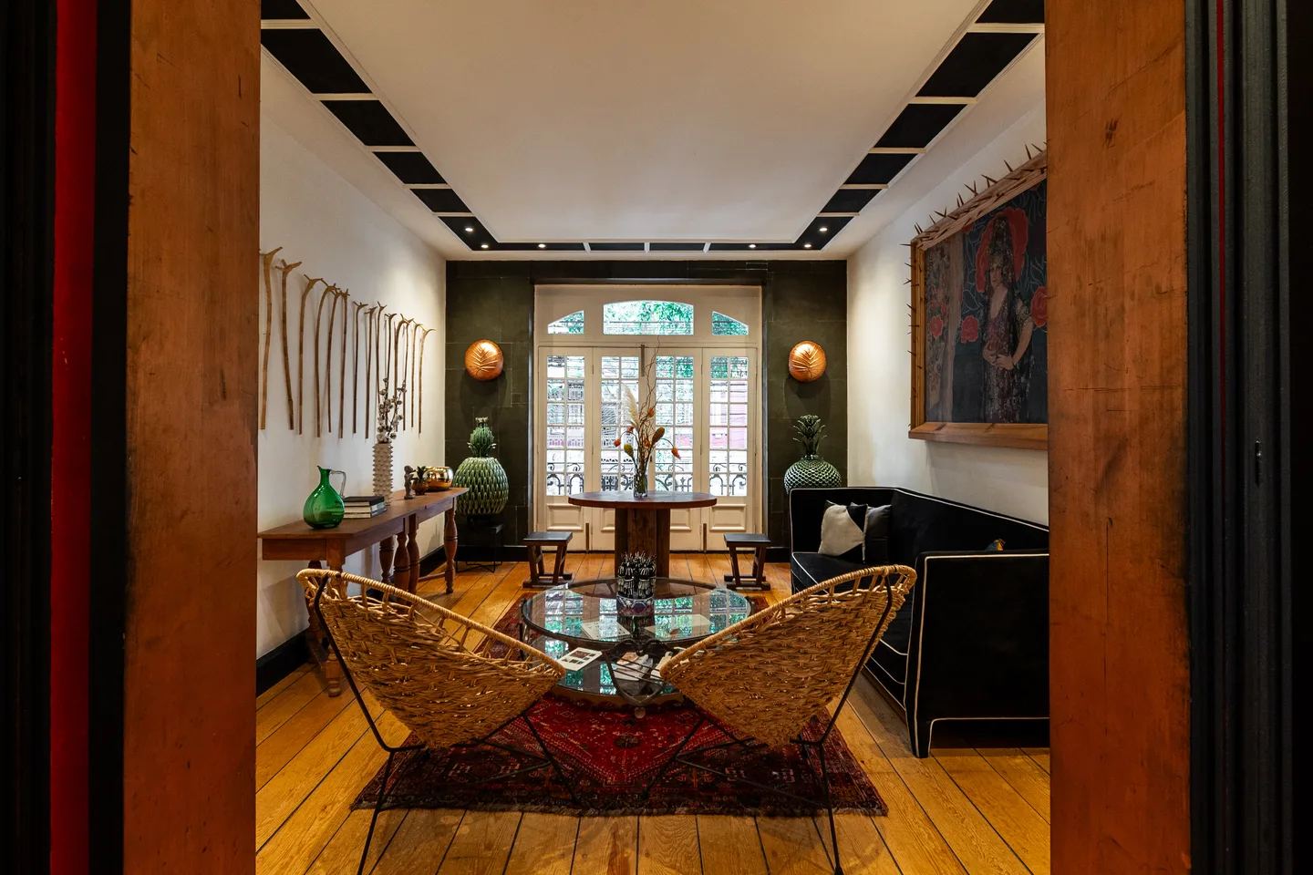 Seating area with woven chairs and arched French doors — Gravity Suite, La Valise Mexico City