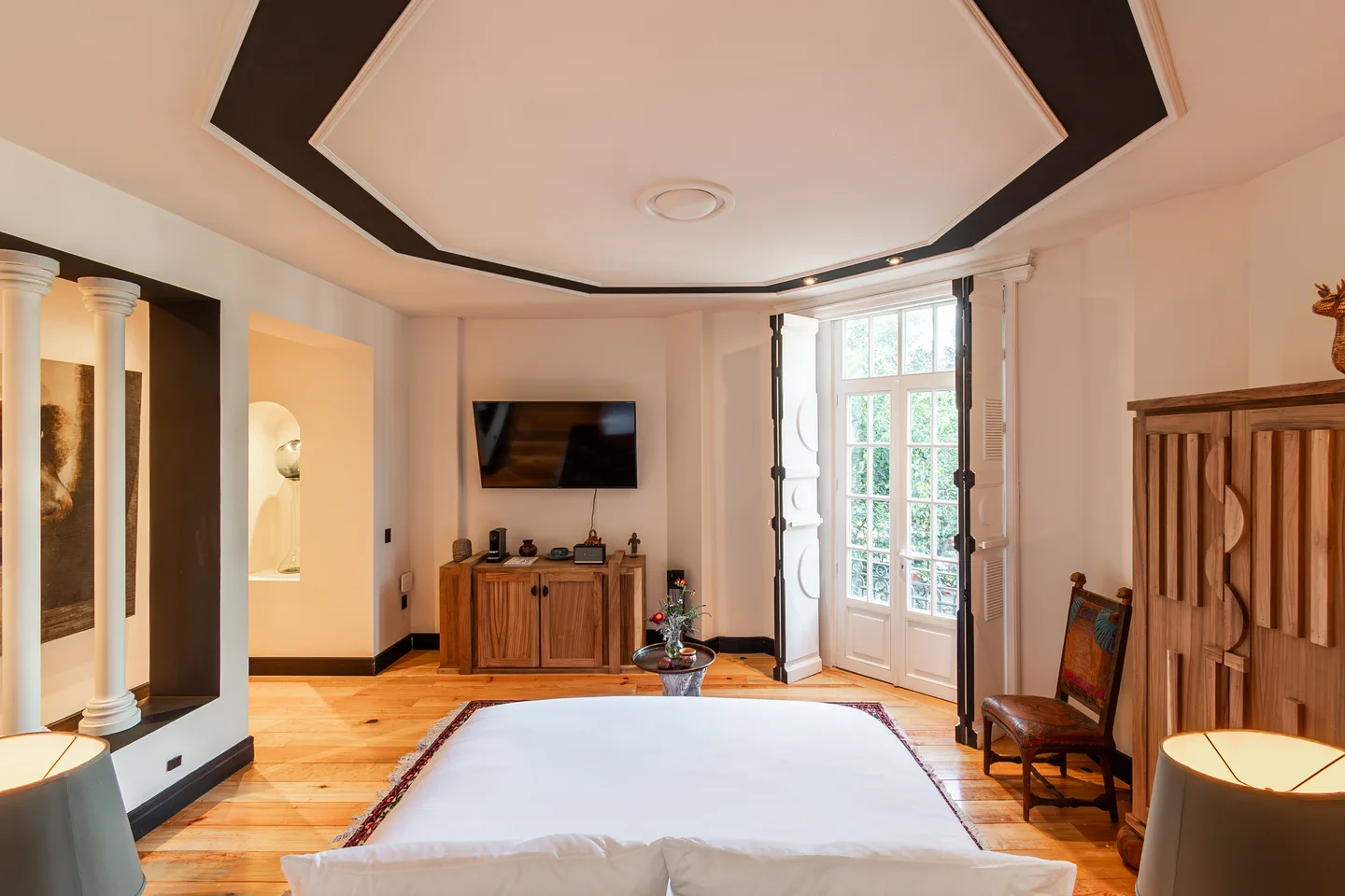 View from the bed toward the TV and balcony doors beneath an octagonal ceiling — Atlas Suite, La Valise Mexico City