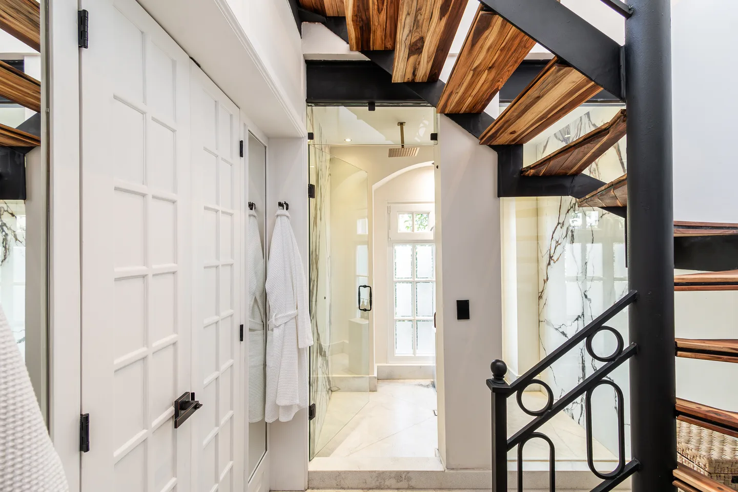 Spiral staircase beside the bathroom with robes hanging — Atlas Suite, La Valise Mexico City