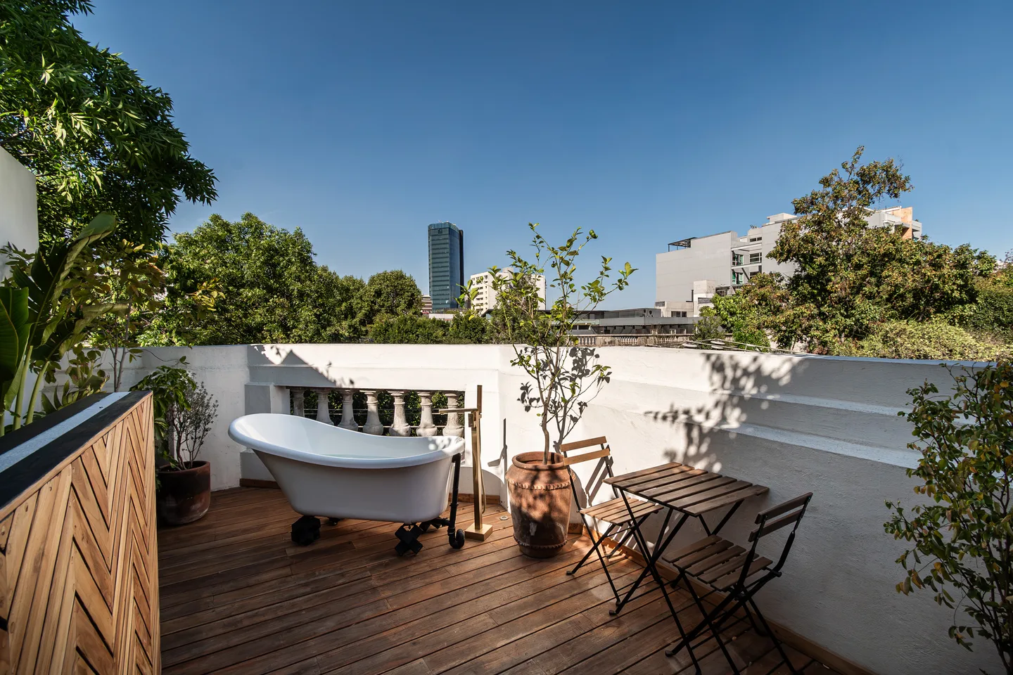 Rooftop terrace with clawfoot bathtub overlooking the treetops and skyline — Atlas Suite, La Valise Mexico City
