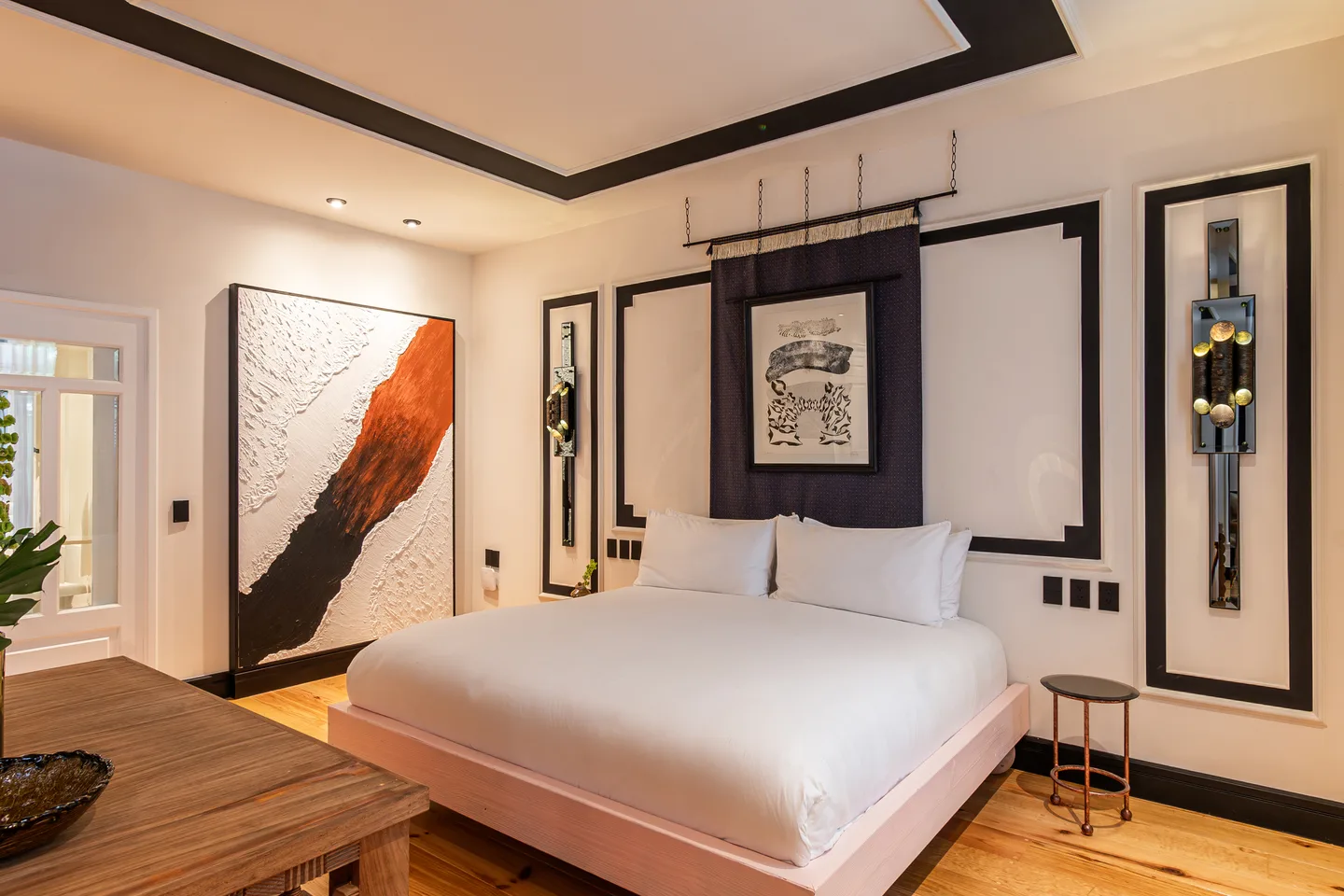 King-size bed beneath framed artwork beside a large textured painting — Halo Suite, La Valise Mexico City