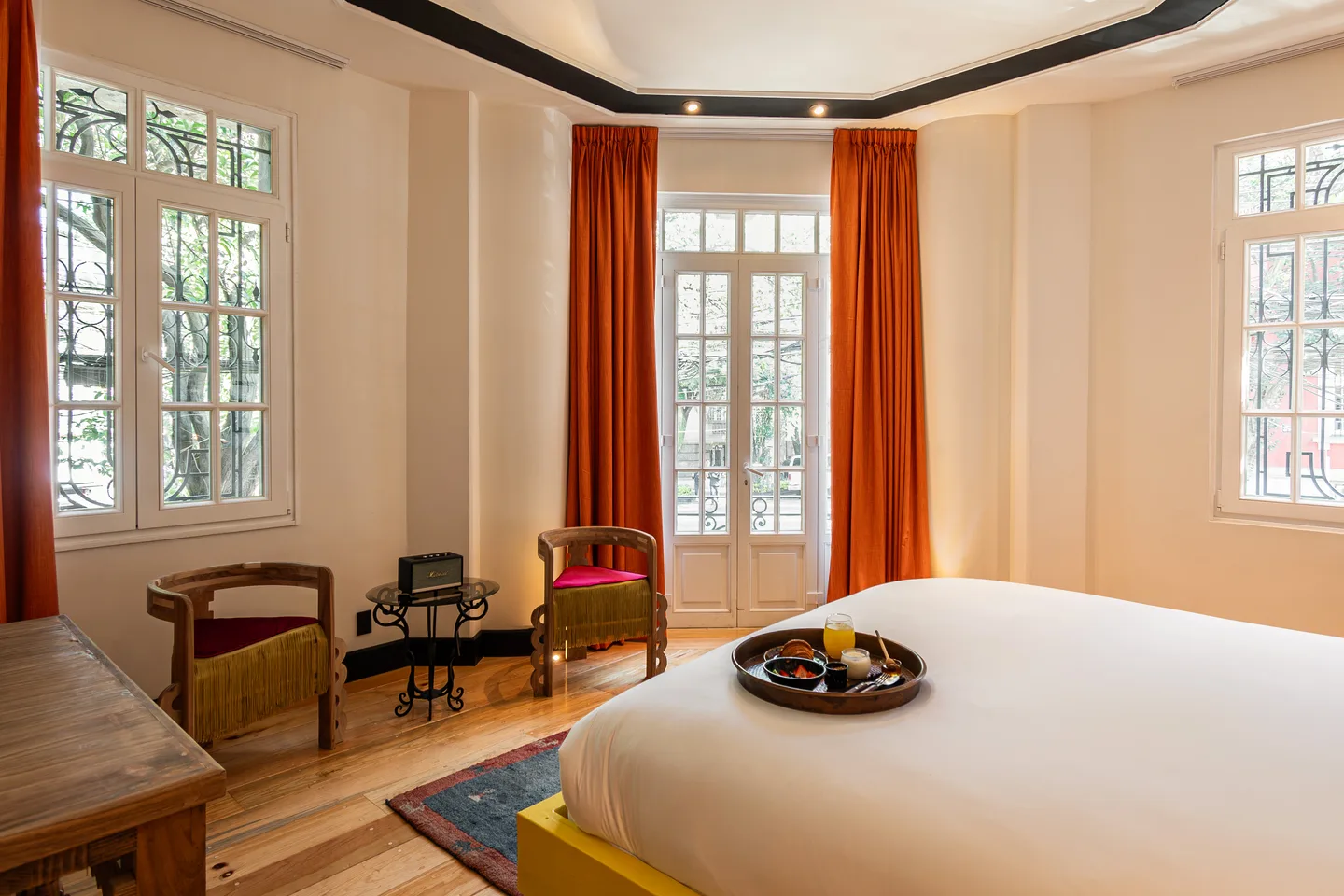 Bed facing the balcony doors and treetops — Nebula Suite, La Valise Mexico City