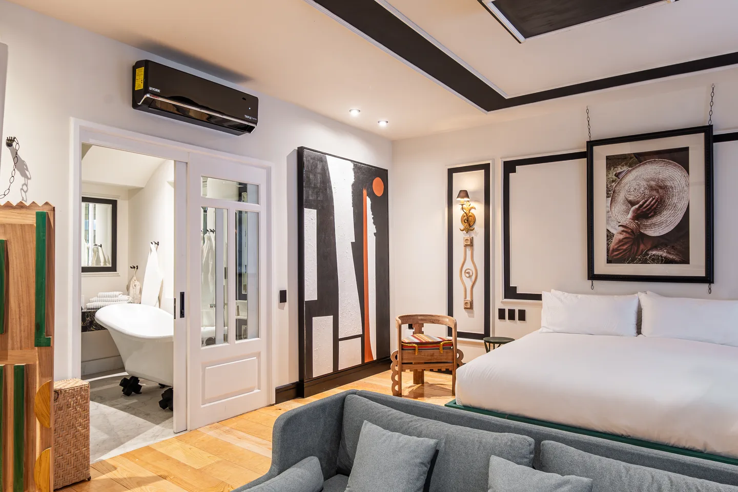 View across the sofa and bed toward the bathroom and bathtub — Nova Suite, La Valise Mexico City