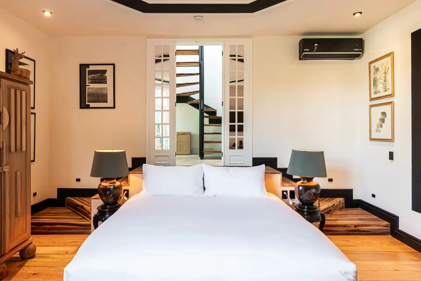 Bright guest room featuring a designer staircase in the background at La Valise Mexico City Hotel.