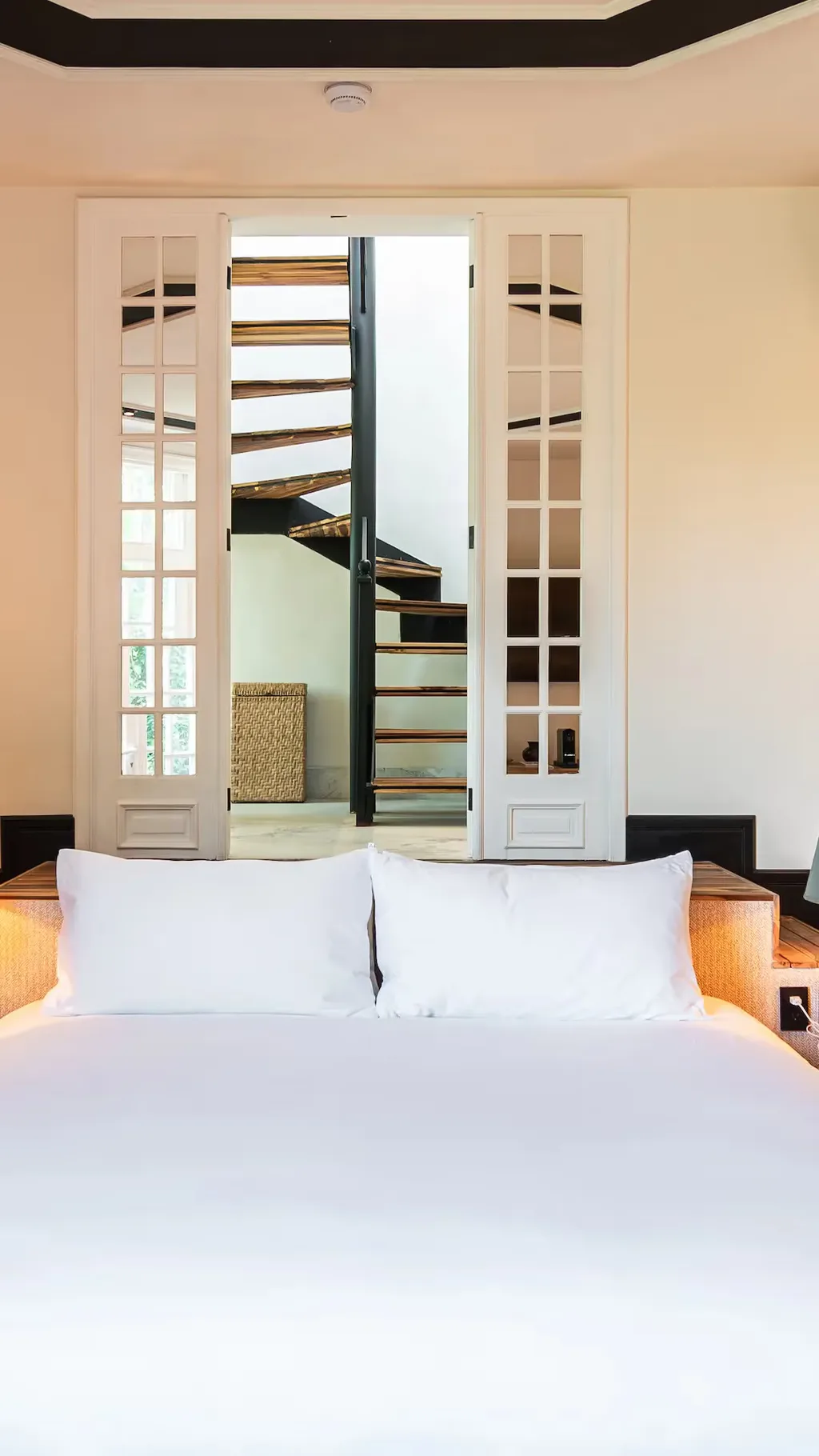 Bright guest room featuring a designer staircase in the background at La Valise Mexico City Hotel.