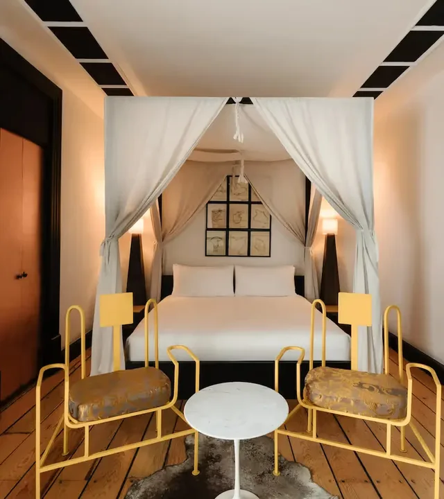 Elegant canopy bed with white drapes in a luxury suite at La Valise Mexico City Hotel.