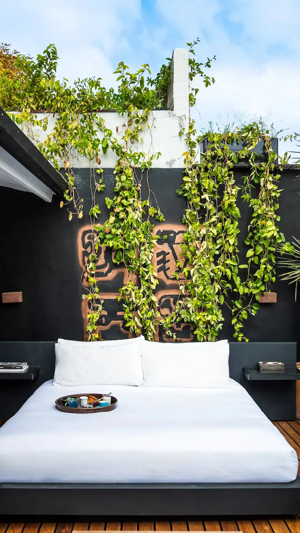 Outdoor bed on a private terrace with a lush green wall at La Valise Mexico City Hotel.
