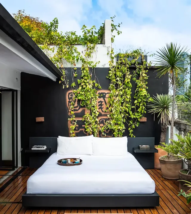 Outdoor bed on a private terrace with a lush green wall at La Valise Mexico City Hotel.